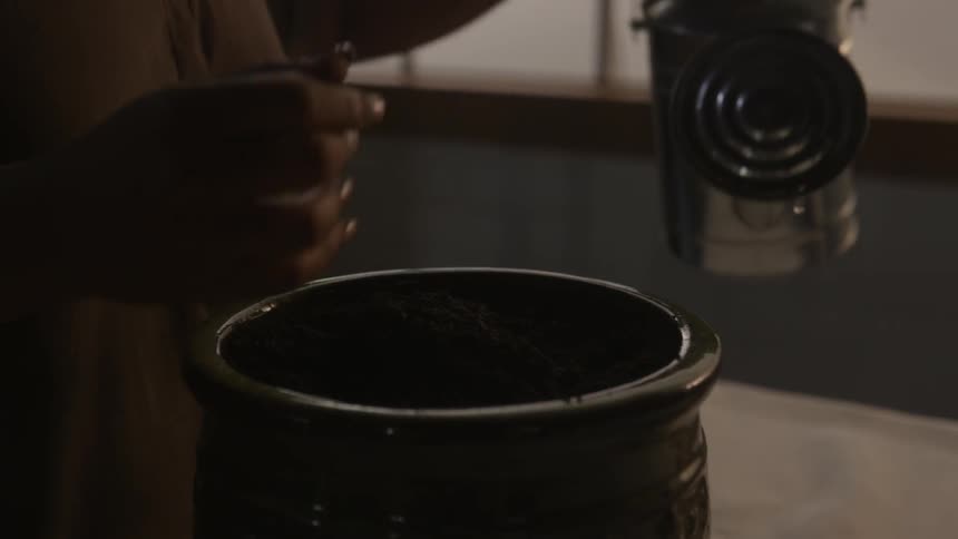 Person presses dirt into a pot