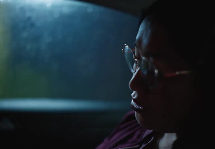 A woman holds her smartphone while on a video call with a young girl as she travels in a car at night