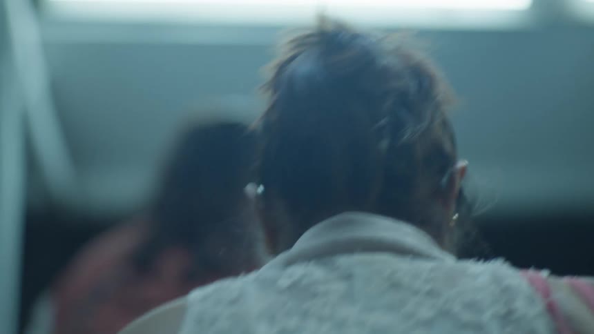 Close up slow motion from behind a woman walking down a dim staircase with other commuters