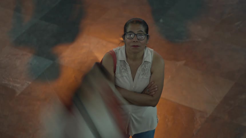Time-lapse, high-angle view of a woman standing perfectly still while a blurred crowd rushes around her