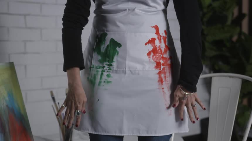 A woman wipes paint on her white apron