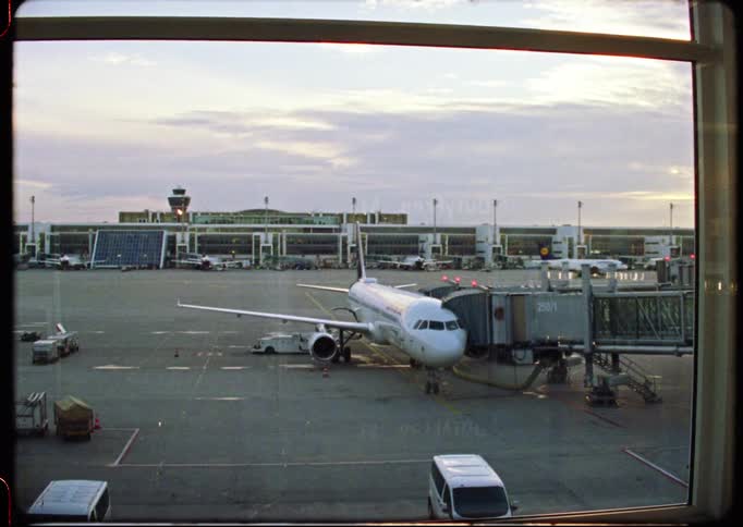 Vintage film shot of a passenger airplane at the terminal gate, waiting for departure