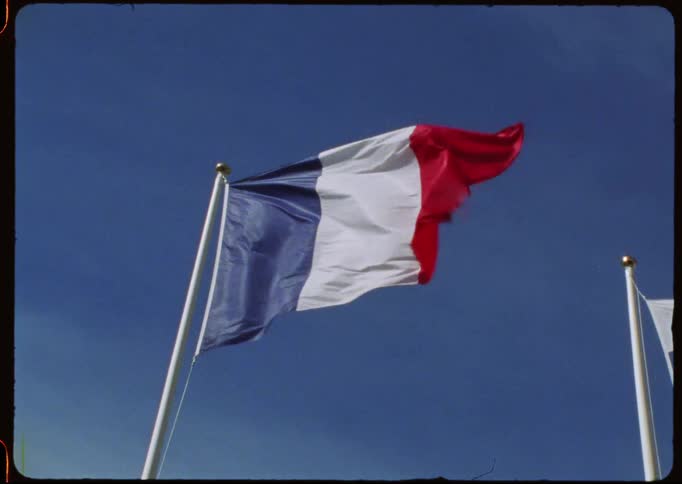 A vintage film shot of the French flag waving slowly in the wind against a clear blue sky