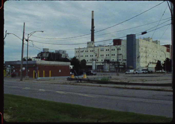 Static vintage shot of a deserted industrial area with a large factory under a cloudy sky