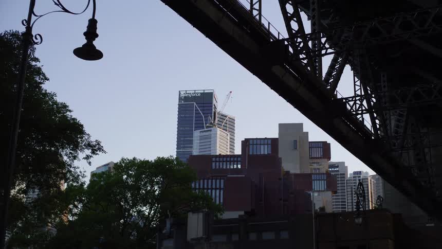 A slow zoom on the Sydney cityscape and Salesforce Tower, framed by the silhouette of the Harbour Bridge and a lamppost