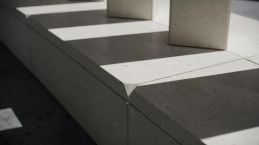 A slow pan reveals geometric shadows moving across the surface of a modern stone architectural feature