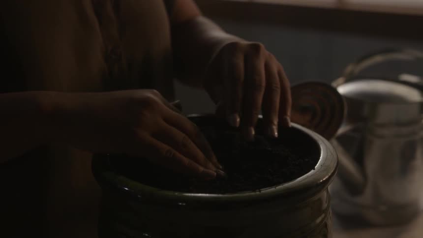 A woman touches the dirt in a pot
