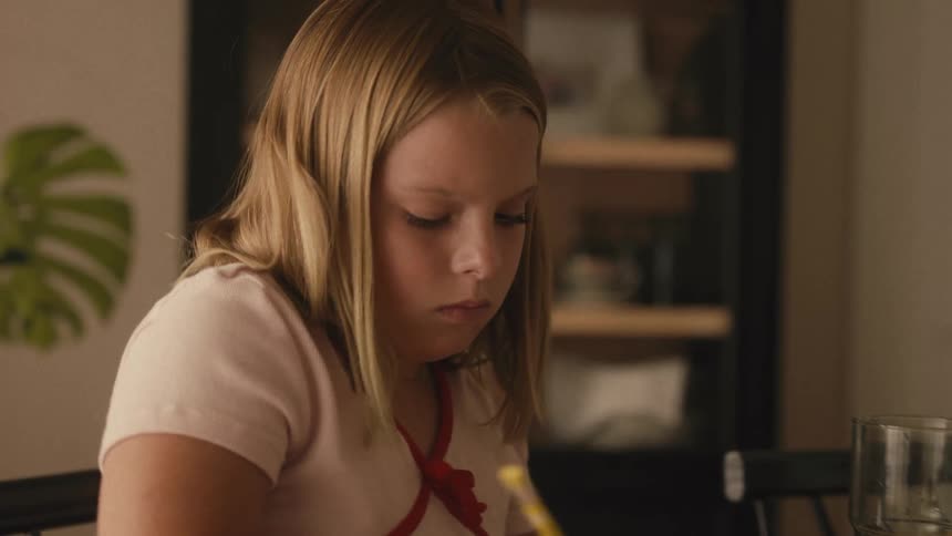 Close-up of a concentrated young girl carefully coloring a rainbow on a piece of paper