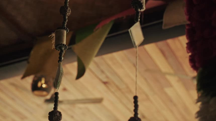 Tibetan prayer flags and beaded decorations gently sway in the breeze from a ceiling fan under a wooden ceiling