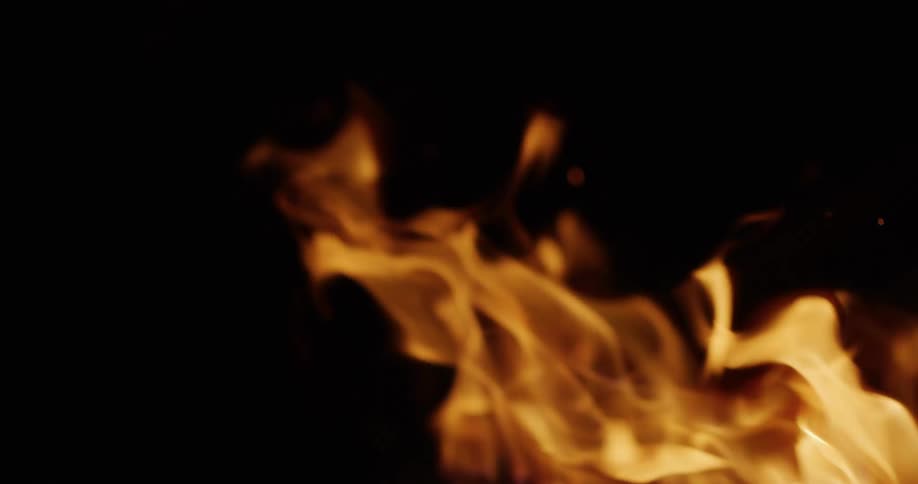 Close-up of bright orange flames burning in slow motion against a black background