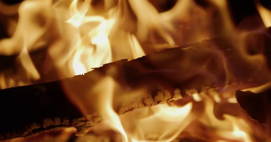 A mesmerizing slow-motion close-up of intense, flickering flames engulfing burning logs