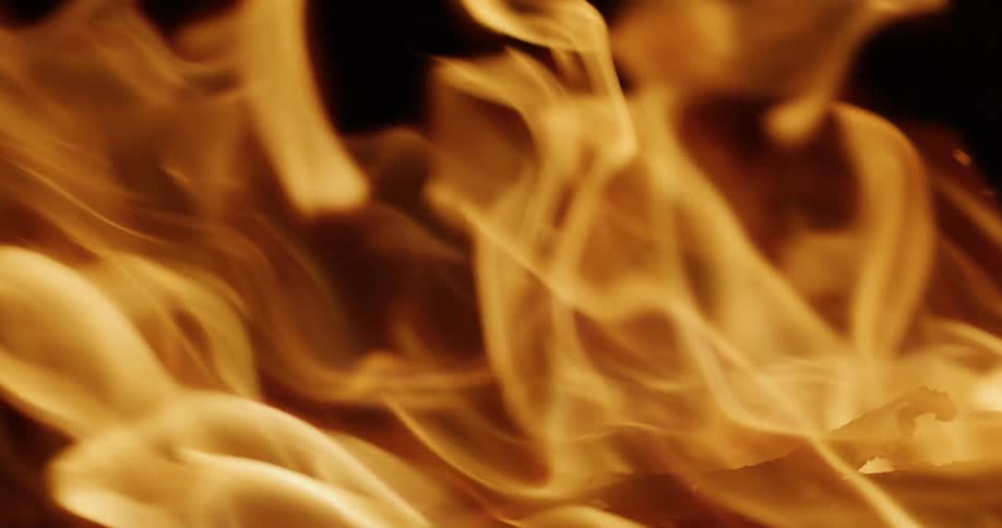A close-up, slow-motion shot of mesmerizing golden flames dancing against a dark background