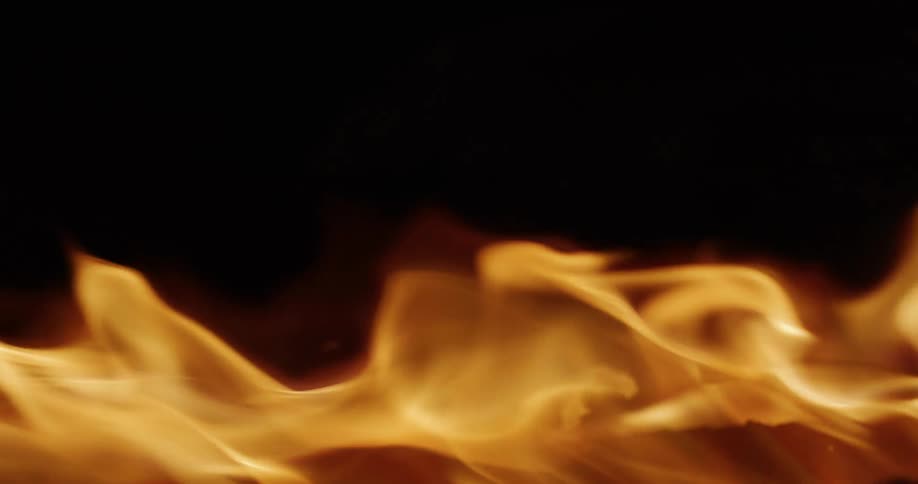 A mesmerizing close-up of slow-motion flames dancing and glowing against a dark black background
