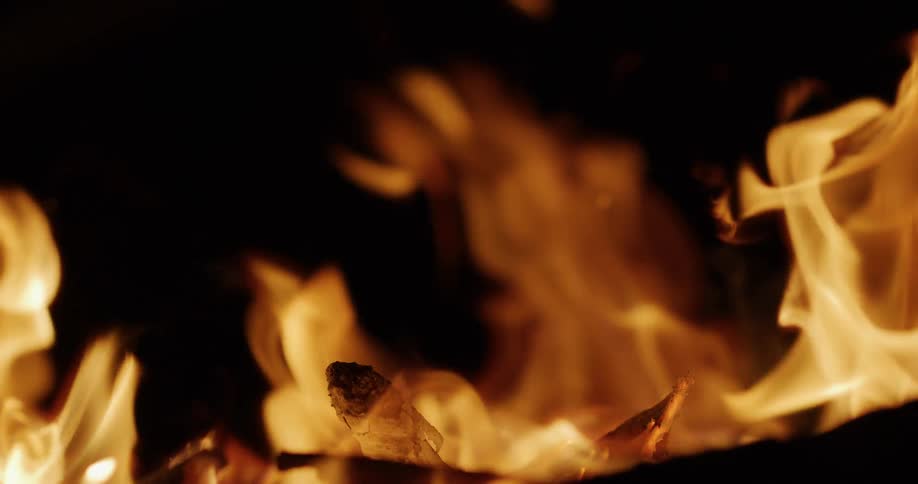 A mesmerizing close-up of a bonfire with dancing flames in slow motion against a dark night