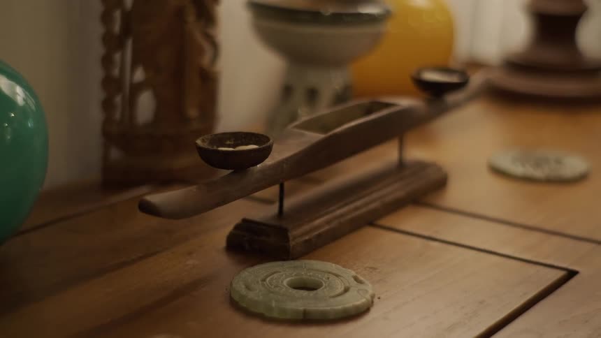 A slow-motion rack focus shot reveals a smoldering sage stick and other spiritual artifacts on a wooden table