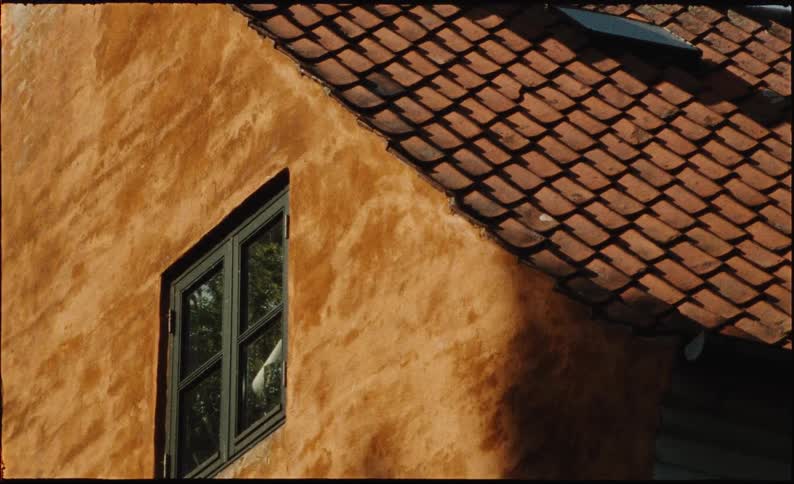 Close up shot on a vintage film of a weathered orange building with a tiled roof