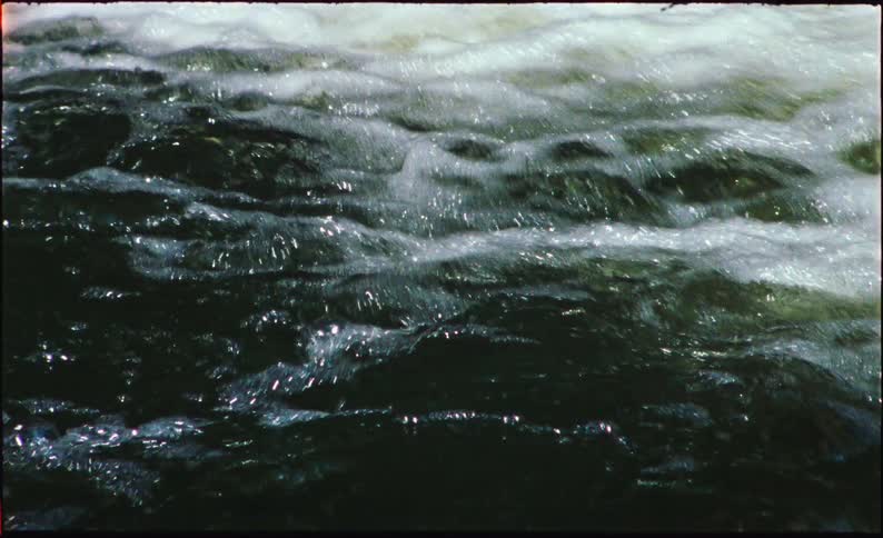 A mesmerizing close-up shot of dark, turbulent water flowing rapidly in a river