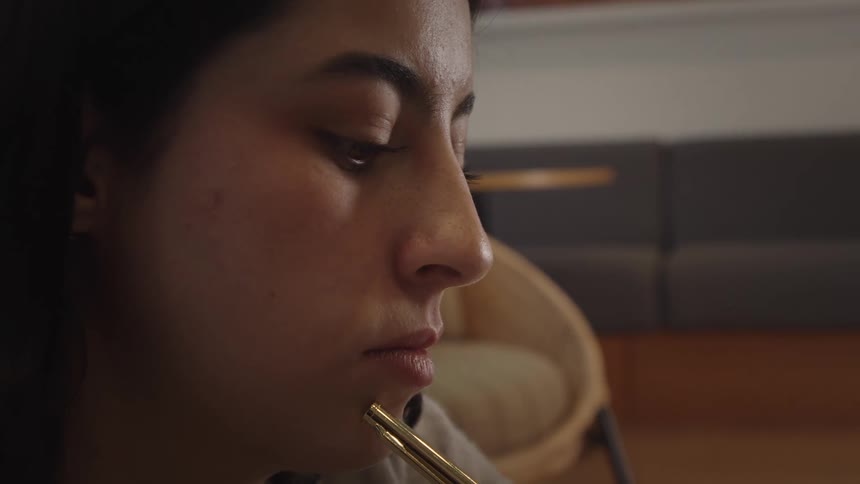 A close-up profile shot of a pensive young woman holding a golden pen to her chin while lost in deep thought