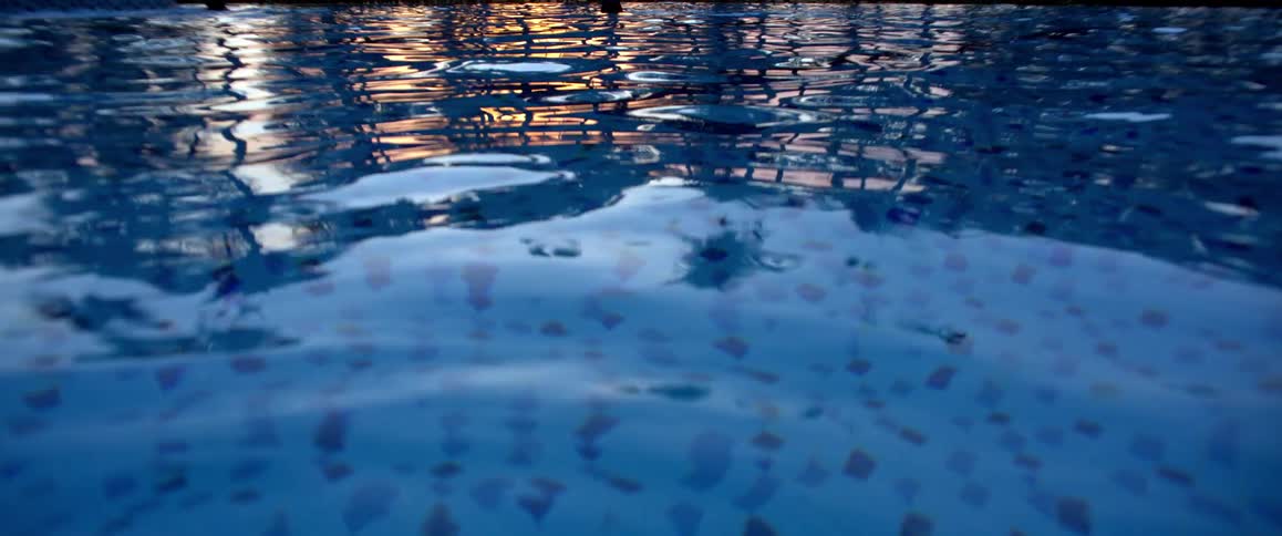 A serene close-up of a swimming pool's rippling surface during a golden sunset