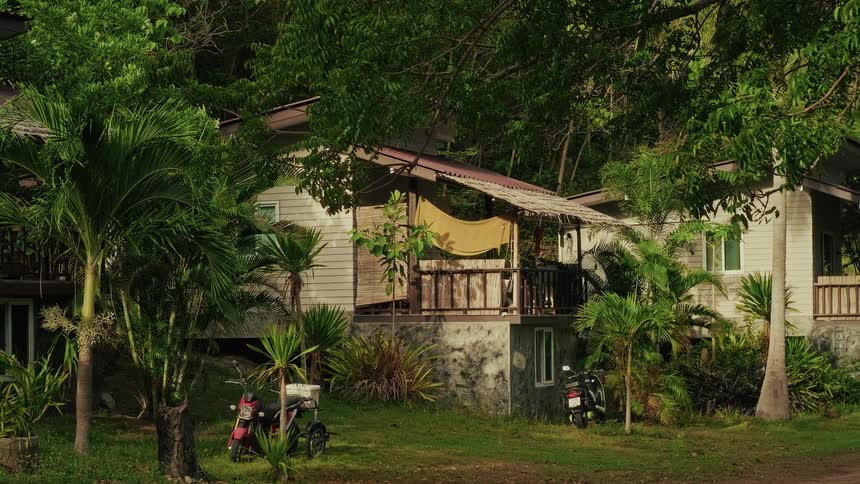 Serene view of rustic wooden bungalows in a tropical setting with gentle sunlight and swaying palm trees