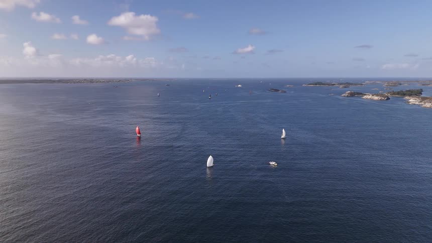 A stunning aerial view captures sailboats gliding across the deep blue sea amidst a beautiful archipelago on a sunny day
