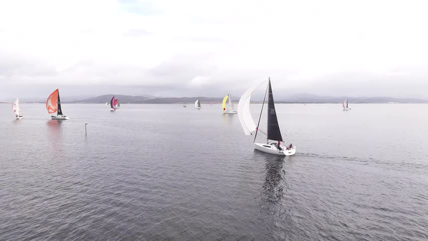 Static aerial shot of multiple yachts with colorful sails competing in a regatta on open water