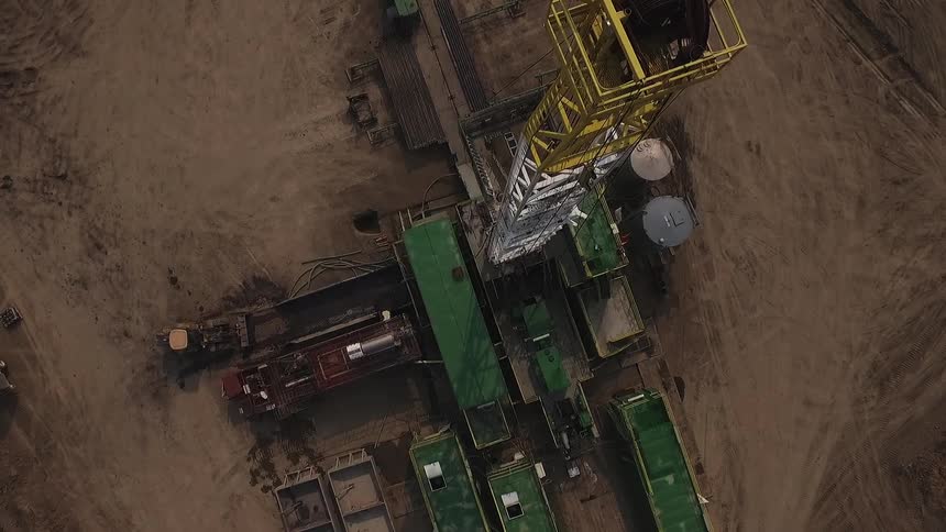 A work site has a tall tower by green buildings