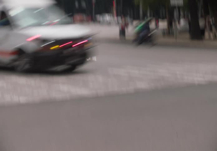 A unique luchador pedestrian traffic light signals 'go' before a blurry whip pan to an ambulance speeding through the city