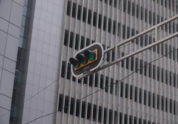 A dynamic zoom shot focuses on a green traffic light with 'CDMX' signage against a modern building in Mexico City
