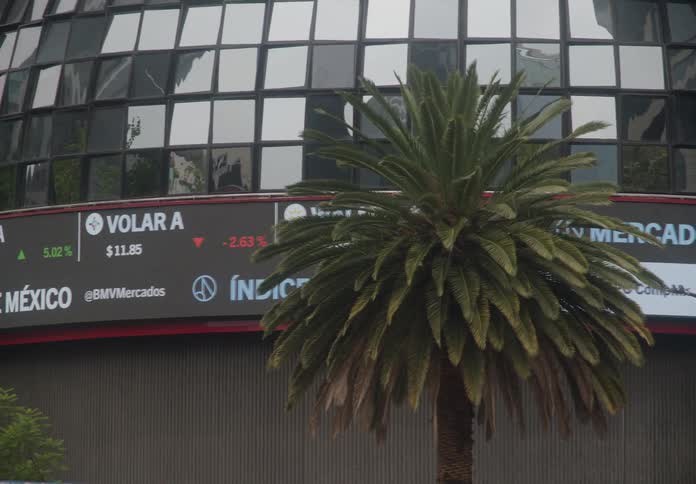 A stock market ticker displays national indices on the curved facade of the Mexican Stock Exchange building in Mexico City
