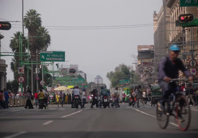 Slow motion shot from the middle of a street showing a crowd of pedestrians and vehicles crossing a busy intersection in Mexico City