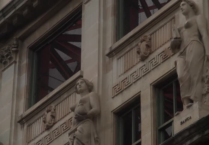 A slow pan across the classical stone statues adorning the facade of a historic building