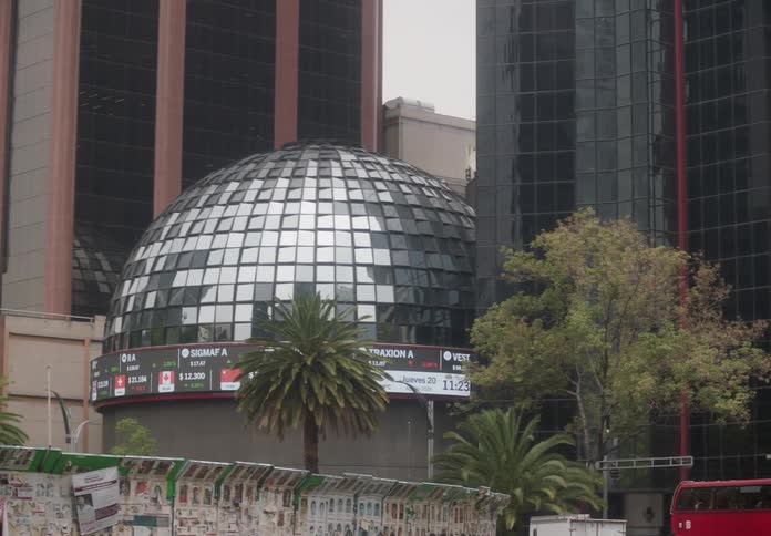 A panning shot reveals the iconic dome of the Bolsa Mexicana de Valores building with a live stock ticker in Mexico City