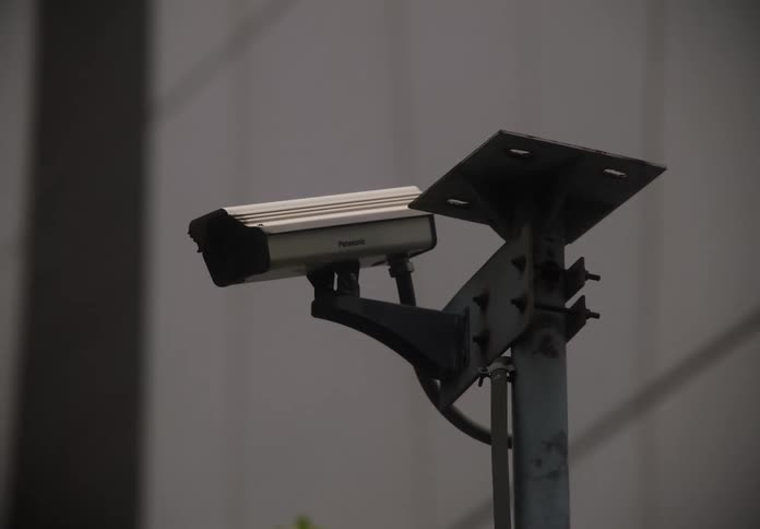 Zooming in on an outdoor surveillance camera with a modern building in the background