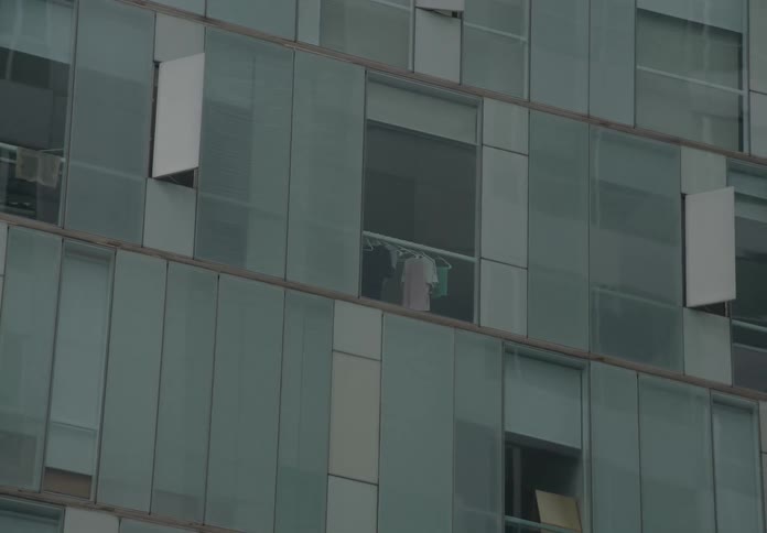 A quick zoom-in to clothes hanging to dry in the window of a modern glass apartment building