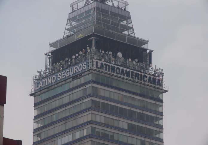 A zoom-in shot reveals the top of the iconic Torre Latinoamericana skyscraper on a hazy day in Mexico City