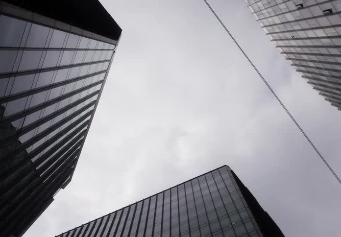 A slow revealing low-angle shot looking up at modern glass skyscrapers against an overcast sky