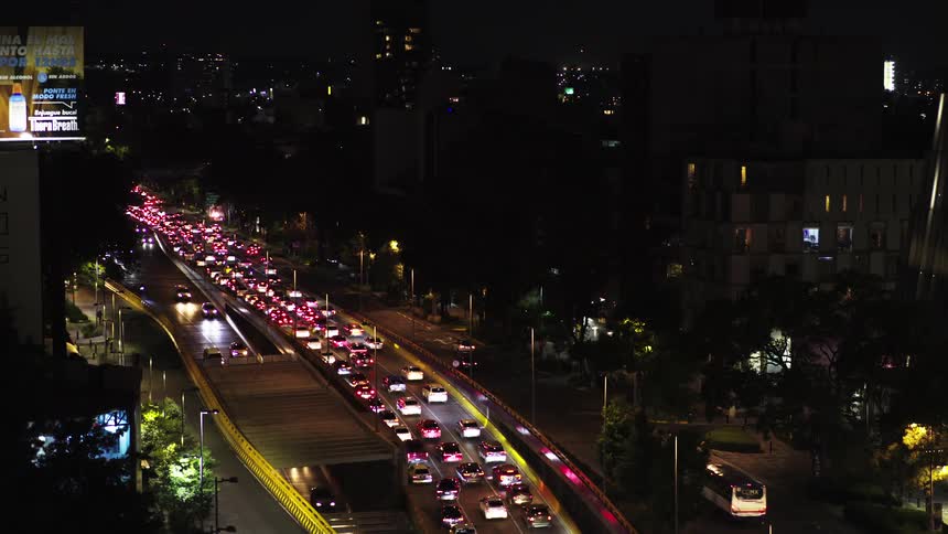 Aerial view tilting down over a congested city highway with heavy traffic at night