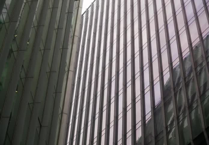 A slow downward tilt reveals the modern architectural details of two glass skyscrapers against a bright sky
