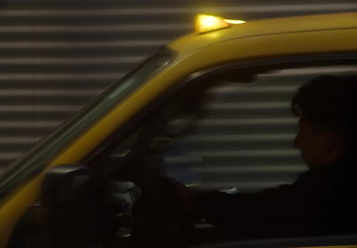 Streaks of light from a passing yellow utility truck with flashing lights create an abstract motion blur of city traffic at night