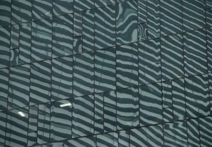 A slow pan reveals the abstract wavy reflections on the glass facade of a modern building