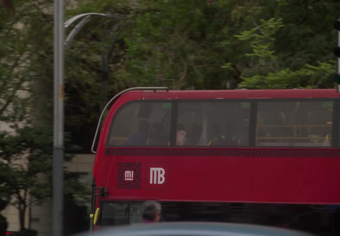 A red double-decker public transport bus moves through the bustling streets of Mexico City in slow motion