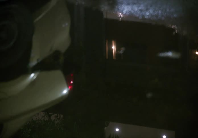 The reflection of an overturned car in a street puddle on a dark, rainy night