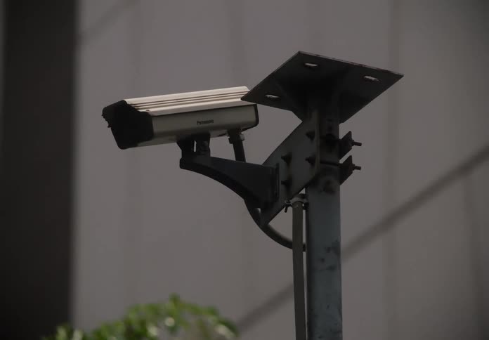 A pan and rack focus shot between a dome and a traditional CCTV camera in an urban setting