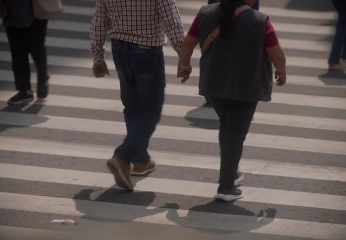 Slow motion shot of a couple holding hands as they walk with a crowd across a city street