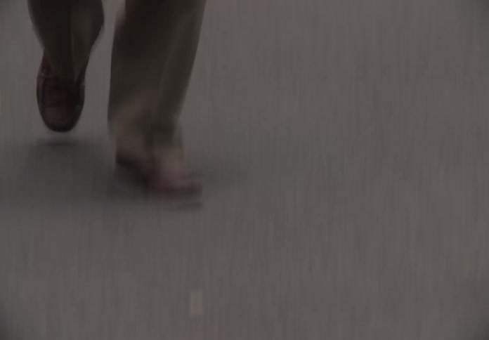 Tracking shot following an older man's feet as he crosses a busy city street and then revealing he is walking past a newsstand