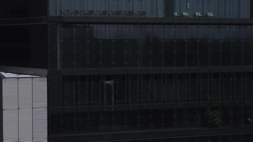 Architectural detail of a contemporary high-rise building with a dark reflective glass facade, slowly zooming out