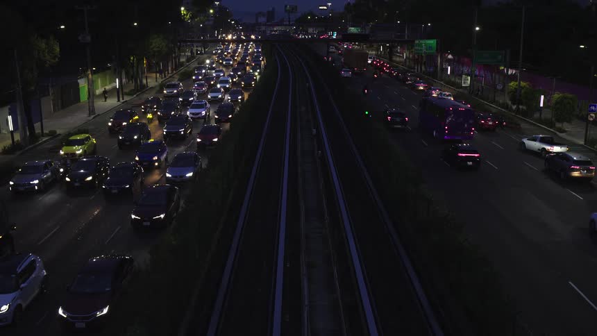 A static, high-angle view captures heavy rush hour traffic on a city highway at night, with headlights blazing