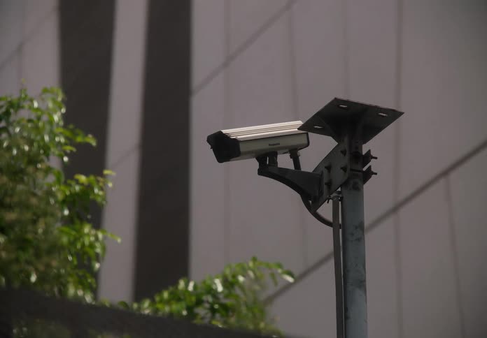A slow zoom-in on a CCTV security camera mounted to a pole in an urban city environment