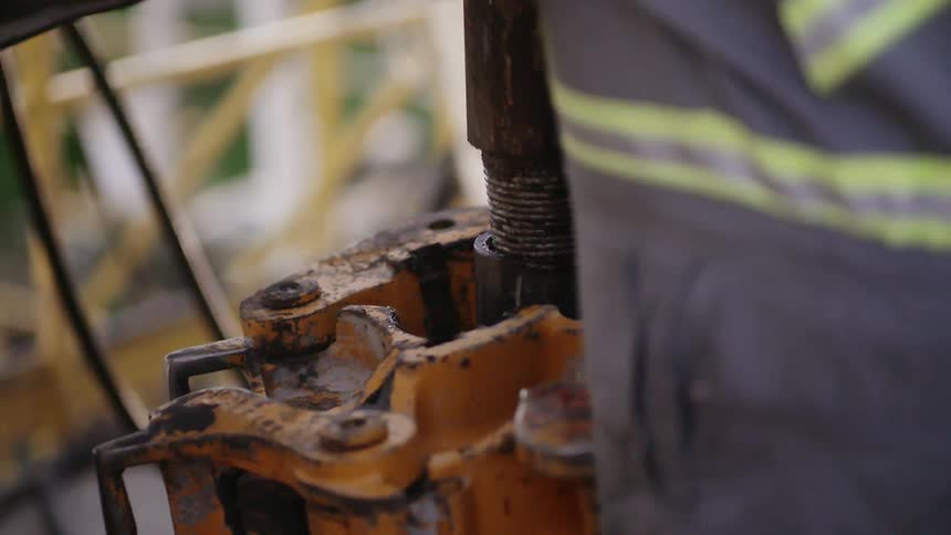 A worker puts a pole into a machine